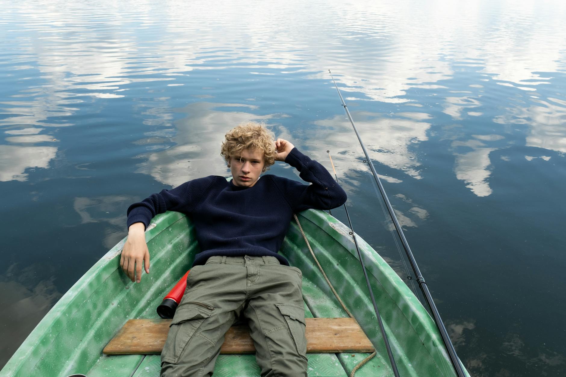 teenager resting in green boat floating on calm waters